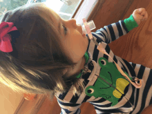 a little girl wearing a striped shirt with a green frog on it