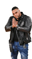 a man wearing a black leather jacket and jeans is praying with his hands folded