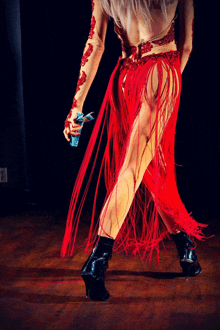 a woman in a red fringed dress is dancing