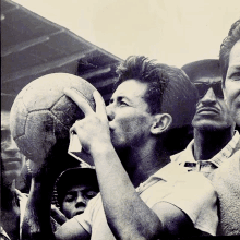 a man is kissing a soccer ball in a crowd of people