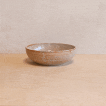 a ceramic bowl sits on a wooden table