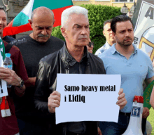 a man holds up a sign that reads samo heavy metal i lidiq