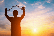 a silhouette of a man holding up a chain