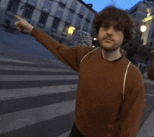 a man in a brown sweater is pointing to the right