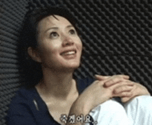 a woman is smiling while sitting in front of a wall with foam .