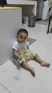 a baby is sitting on the floor holding a toy and wearing a shirt that says ' snoopy ' on it