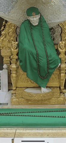 a statue of a man in a green robe is sitting on a throne