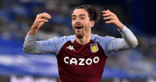 a soccer player wearing a maroon and blue jersey is celebrating a goal during a soccer match .