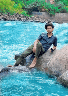 a young man sits on a rock in the water