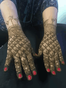 a woman 's hands are decorated with henna and have red nail polish