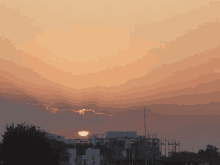 the sun is setting over a city with a few buildings in the foreground