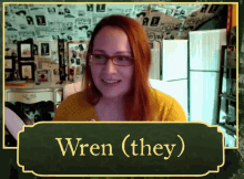 a woman wearing glasses is smiling in front of a sign that says wren ( they)