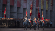 a group of soldiers marching in a parade with flags including one that has the letter a on it