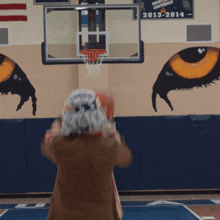 a man in a patriotic costume throws a basketball in front of a basketball hoop that says 2013-2014 on it