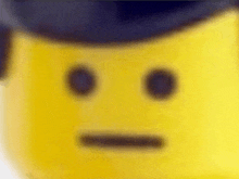 a close up of a yellow lego man 's face with a hat on .