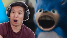 a man wearing headphones next to a blue stuffed animal with its mouth open