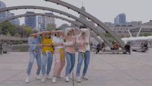 a group of young people are dancing in front of a bridge with a sign that says ' a ' on it