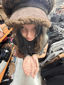 a girl wearing a hat holds her hands out in front of a shelf with a bag that says purse bag on it