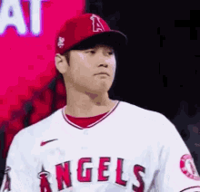 a baseball player wearing a red hat and a white jersey is standing in front of a red background .