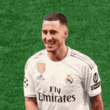 a soccer player is wearing a fly emirates jersey and smiling .