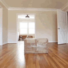 a cardboard box wrapped in plastic sits on a wooden floor