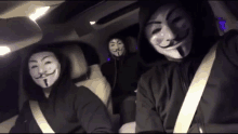 three people wearing anonymous masks are sitting in the back seat of a car