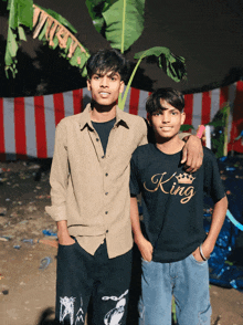 two boys posing for a picture one wearing a king shirt