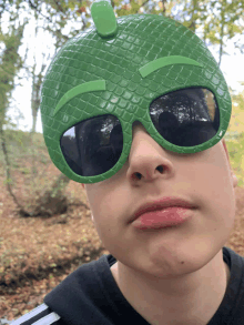 a boy wearing a green mask and sunglasses is making a funny face