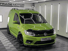 a green van is parked in a trade motor group showroom