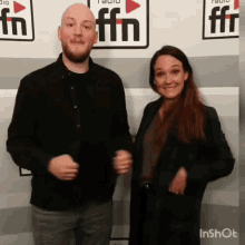 a man and a woman are posing for a photo in front of a wall with ffn written on it