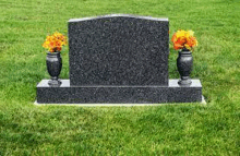 a gravestone in a cemetery with two vases of flowers .