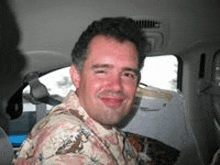 a man is sitting in the back seat of a car and smiling at the camera .