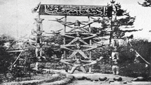 a black and white photo of a group of people standing on top of each other on a tower .