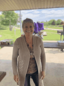 a woman wearing a tan sweater and leopard print top smiles for the camera