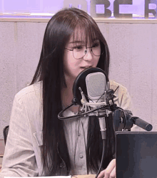 a woman wearing glasses is talking into a microphone in front of a sign that says bcr