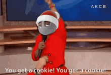 a cartoon character in a santa hat is holding a microphone and says you get a cookie