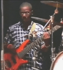 a man in a plaid shirt is playing an orange guitar