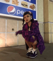 a girl squatting in front of a pepsi ad