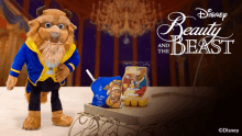 a disney beauty and the beast mascot stands next to a bag of popcorn