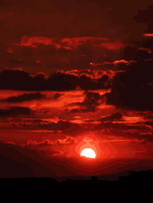 a sunset with red clouds and the sun in the middle