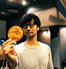 a man wearing glasses is holding up a fried food item