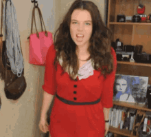 a woman in a red dress stands in front of a bookshelf with a picture of a woman on it