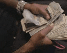 a person is holding a large pile of money in their hands .