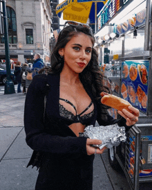 a woman in a bra is eating a hot dog in front of a sprite sign