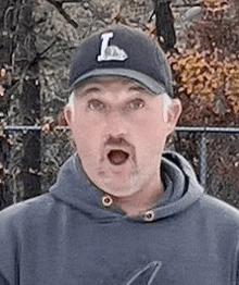 a man wearing a baseball cap and hoodie is making a funny face .