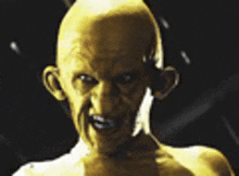 a bald man with a yellow face and ears is standing in the dark looking at the camera .