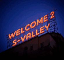 a neon sign that says welcome 2 s-valley on top of a building