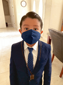 a young boy wearing a blue face mask and a blue suit