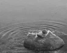 a child is laying on a rock in the water