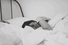 a woman sleeping in a bed with white sheets